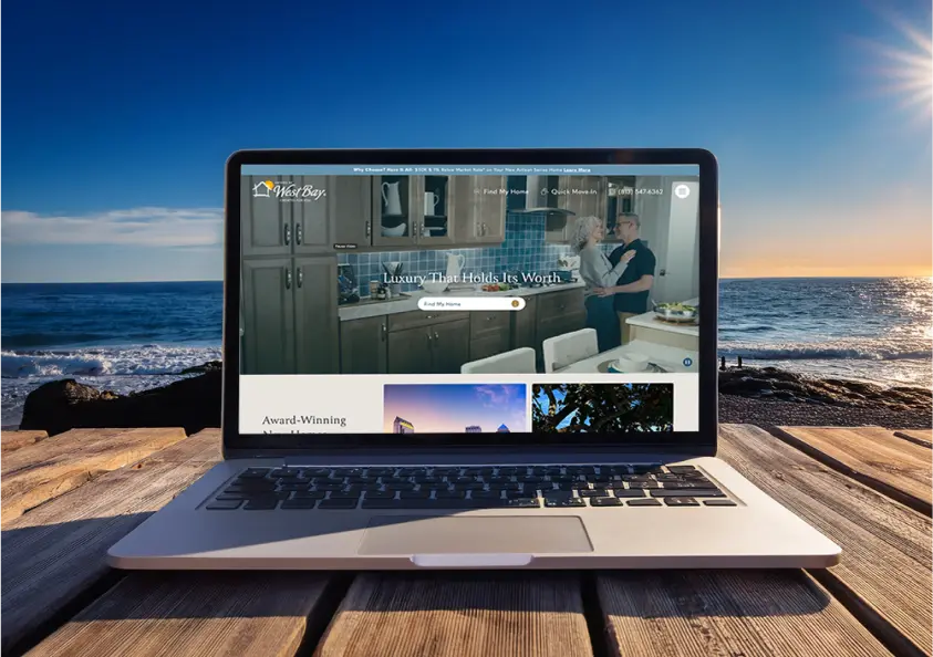 Laptop on beachfront displaying Homes By WestBay website